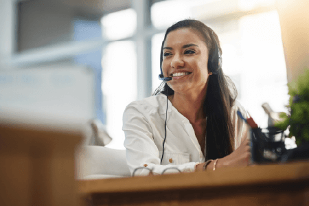 Woman at a desk with a headset on, smiling