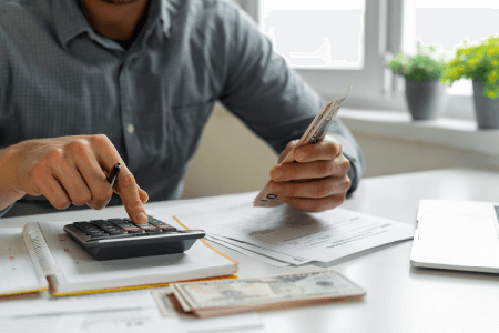 Person holding cash while using a calculator