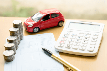 Red toy car next to stacks of change and a calculator