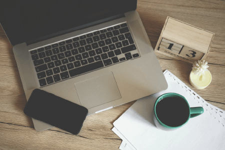 A table with a laptop, phone, and coffee
