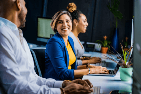 woman at laptop, smiling at a coworker