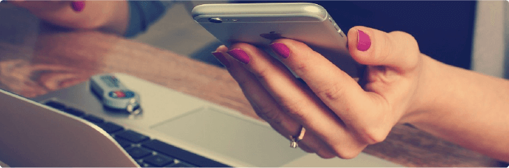 cellphone next to laptop and notebook on wooden desk