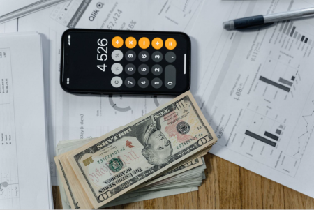 A cellphone and cash on top of paper documents