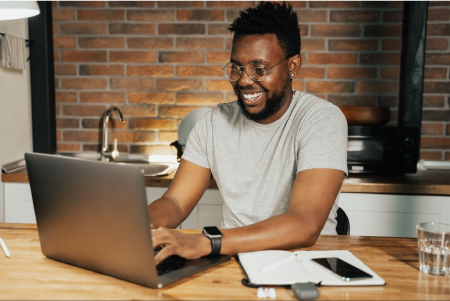 A man smiling while at his laptop.
