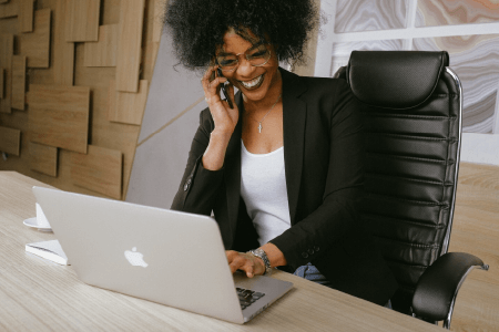 Woman smiling while on the phone and at a computer