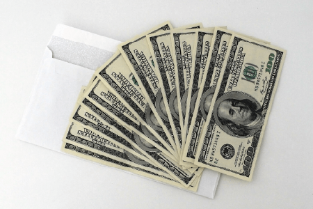 cash fanned out, laid over an open envelope