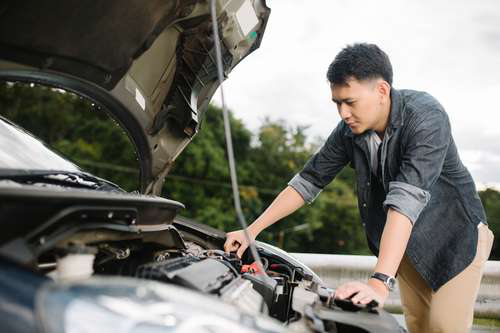 Person performing car repairs outdoors without a garage – practical solutions for vehicle maintenance.