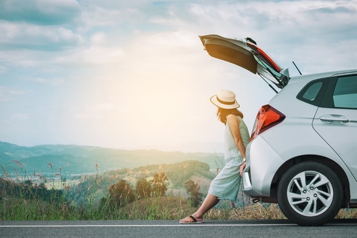 Woman leaning on the back of a white car