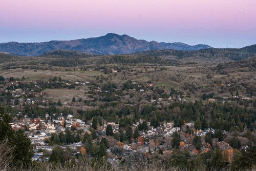 Aerial view of the town of Santa Rosa, California, nestled in a valley at sunset beneath a mountain.
