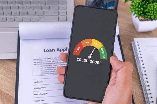 Man holding a phone to check his credit score after resolving outstanding debts