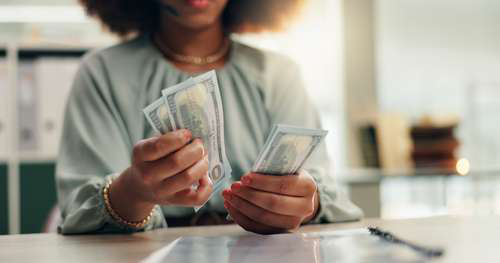A employee counting a stack of bills, representing the process of paying out funds from a title loan or cash advance.